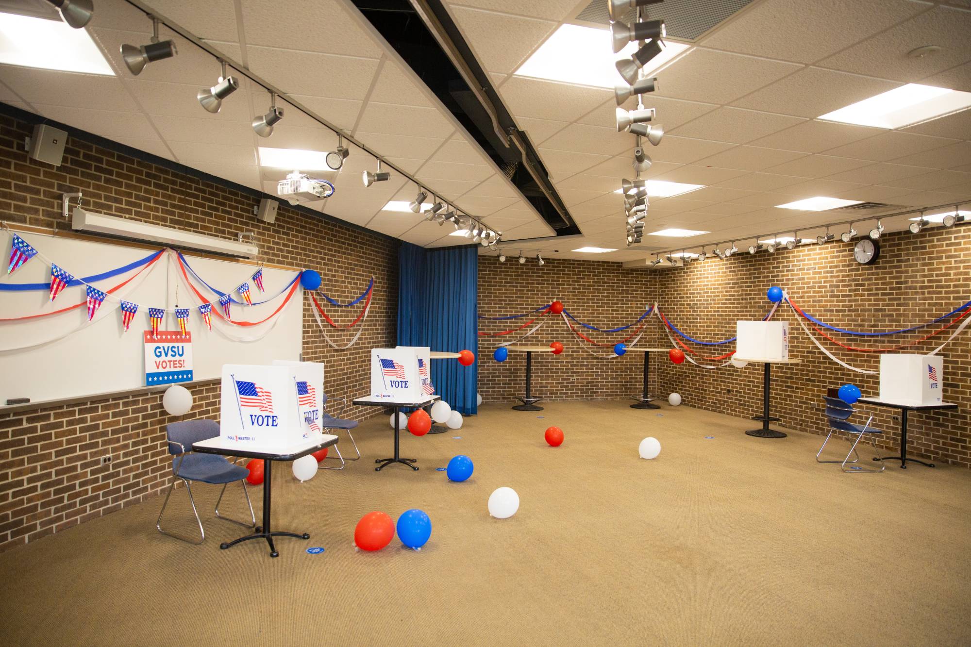 Several voting booths with red, white, and blue decorations and balloons.